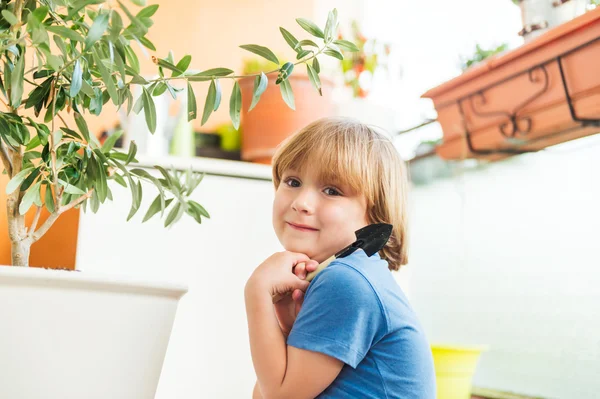 Schattige kleine jongen spelen met tuingereedschap op het balkon — Stockfoto