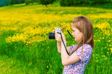 Holding bir kamera ve sarı düğünçiçekleri buket doğa fotoğraflarını sevimli küçük kız