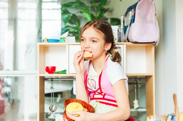 Χαριτωμένο κοριτσάκι παίζει στο σπίτι, να τρώει μπισκότα — Φωτογραφία Αρχείου