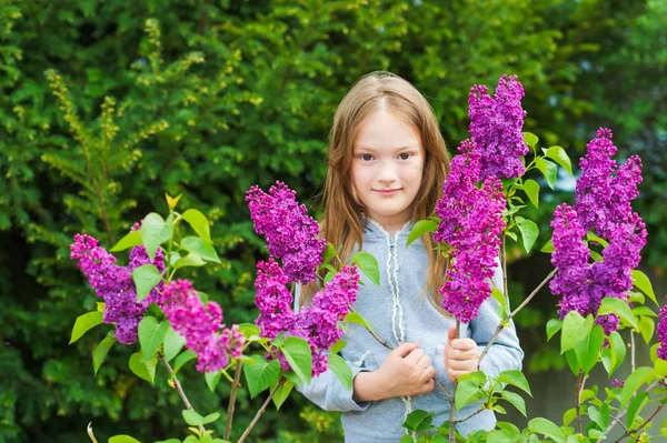 Outdoor portrait of a cute little girl against beautiful lilac on a nice spring day — Stock Photo, Image