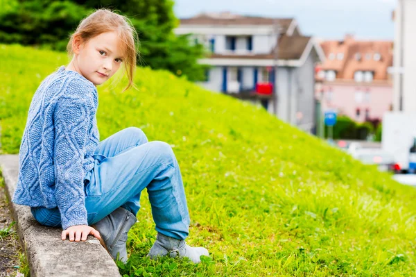 青いニットのプルオーバーにベルト付きジーンズを身に着けている 7 歳のかわいい女の子のファッション ポートレート — ストック写真