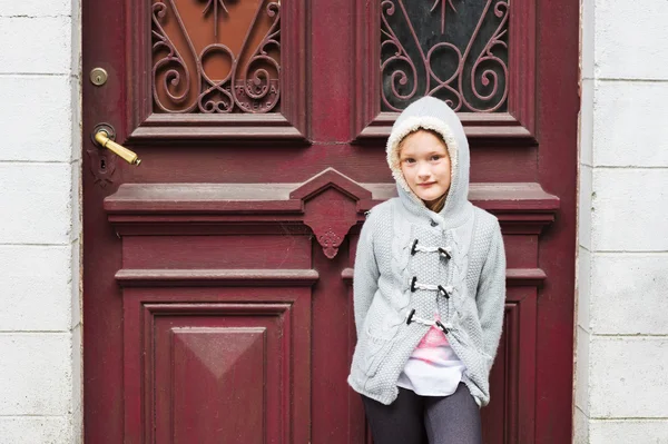 Außenporträt eines niedlichen kleinen Mädchens in einer Stadt, das eine graue Strickjacke trägt — Stockfoto