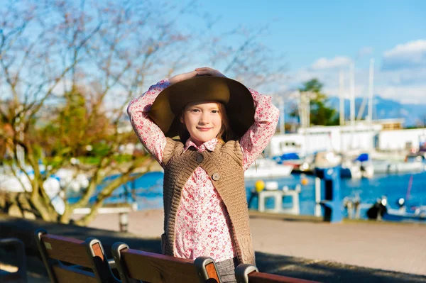 Cute little girl of 7 years old playing outdoors, wearing big hat Royalty Free Stock Photos