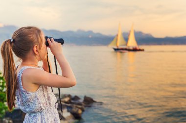 Açık teknede dürbünle bakarak gölün güzel sıcak bir akşam üzerinde oynarken bir sevimli küçük kız portresi