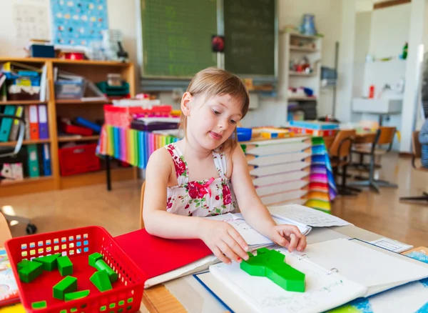 Schattig klein meisje werken in een klaslokaal — Stockfoto