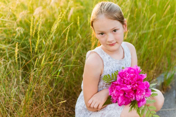 Close up portrait of a cute little girl with beautiful pink peonies — Stock Photo, Image