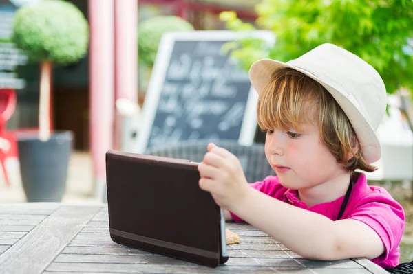 Lindo niño jugando con la tableta PC en un café —  Fotos de Stock