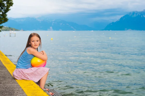 Süßes kleines Mädchen, das sich bei Sonnenuntergang am See ausruht — Stockfoto