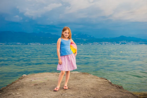 Nettes kleines Mädchen, das am Abend am See spielt — Stockfoto