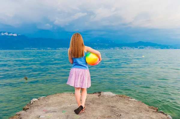 Cute little girl playing by the lake in the evening — Stock Photo, Image