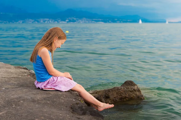 Cute little girl playing by the lake in the evening — Stock Photo, Image