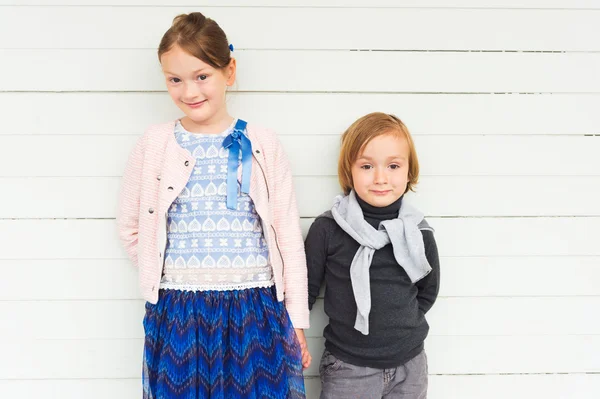 Twee mode kinderen tegen witte houten muur — Stockfoto