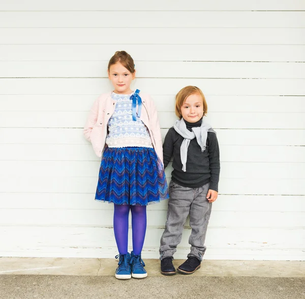 Два модных ребенка против белой деревянной стены — стоковое фото