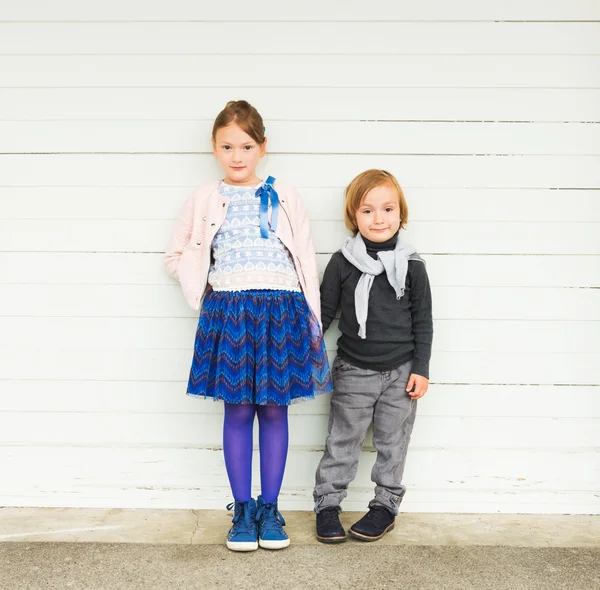 Twee mode kinderen tegen witte houten muur — Stockfoto