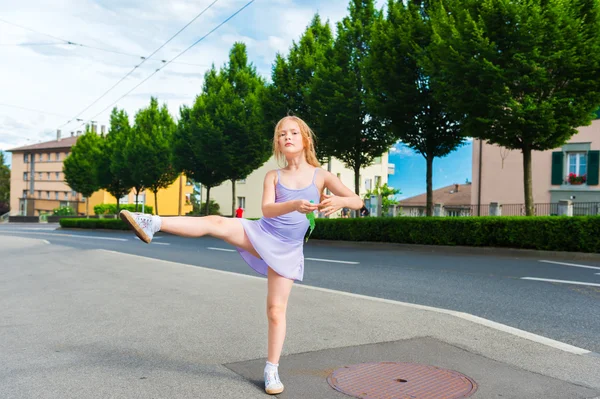 Retrato al aire libre de una linda niña de 7 años, caminando a la escuela de baile y bailando en la calle, vistiendo vestido de ballet púrpura — Foto de Stock