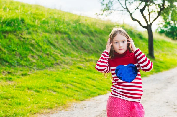 Outdoor portrait of a cute little girl of 7 years old at sunset, wearing red pullover — Stok fotoğraf