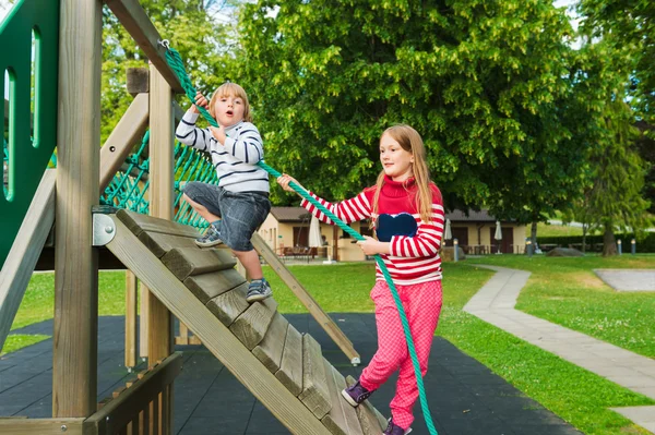 Bonito crianças se divertindo no playground, vestindo pulôveres quentes — Fotografia de Stock