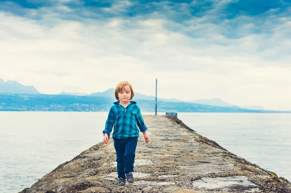 Cute little boy walking on a pier, wearing emerald shirt and trousers — Stok fotoğraf