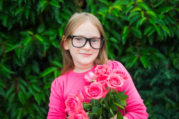 Menina adorável vestindo óculos, segurando rosas rosa brilhante — Fotografia de Stock