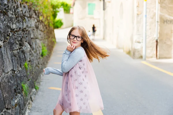 Außenporträt eines niedlichen kleinen Mädchens in einer Stadt mit Brille und Kleid — Stockfoto