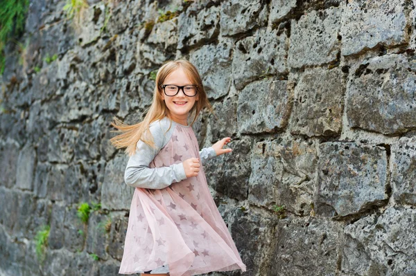 Outdoor portrait of a cute little girl in a city, wearing eyeglasses and dress — Stock Photo, Image