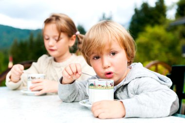 Açık havada sıcak çikolata içme, iyi vakit tatile Alp dağlarında sevimli çocuklar