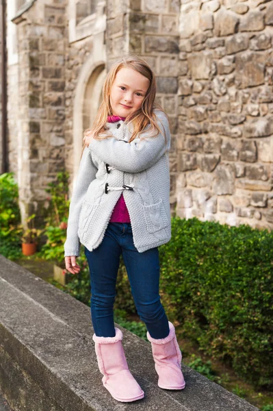 Außenporträt eines niedlichen kleinen Mädchens in einer Stadt an einem schönen Tag, mit grauer Jacke und rosa Stiefeln — Stockfoto