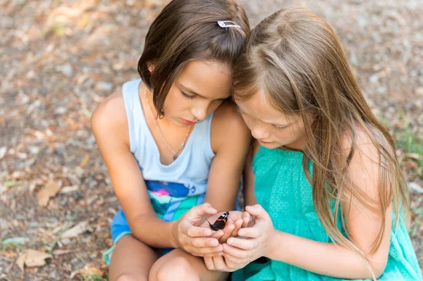 Cute girls playing with butterfly outdoors in the park on a nice summer day — Stok fotoğraf