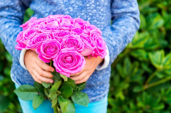 Beautiful bright pink roses in child's hands — Zdjęcie stockowe