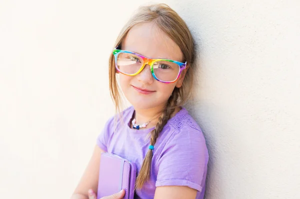 Entzückendes kleines Mädchen spielt auf einem digitalen Tablet und trägt eine Regenbogenbrille — Stockfoto