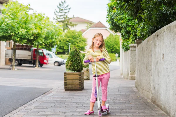 Outdoor portrait of a cute little girl on a scooter — Stock Photo, Image