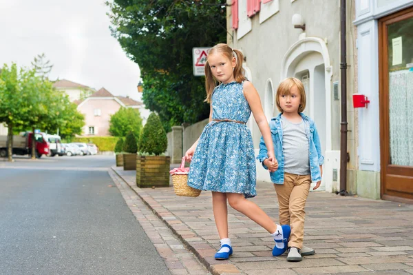 Portret van de mode kinderen in een stad, schattige kinderen poseren buitenshuis, schattig klein meisje en haar broer dragen van blauwe kleding — Stockfoto