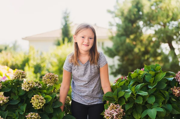 Retrato ao ar livre de uma menina bonita de 8 anos de idade ao lado de hortênsia — Fotografia de Stock