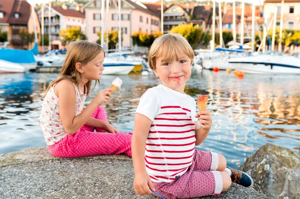 Портрет двух очаровательных детей, поедающих красочное мороженое на открытом воздухе — стоковое фото