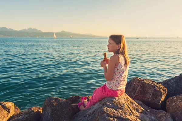 Außenporträt eines süßen kleinen Mädchens, das Eis isst und sich bei Sonnenuntergang am Genfer See ausruht — Stockfoto