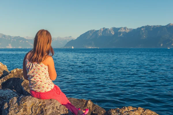 Outdoor portrait of a cute little girl resting by the lake Geneva at sunset, back view — Stok fotoğraf