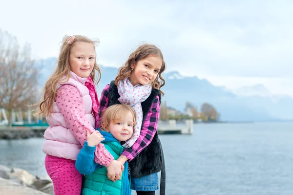На відкритому повітрі портрет трьох милих маленьких дівчат, одягнених у теплі пальто — стокове фото