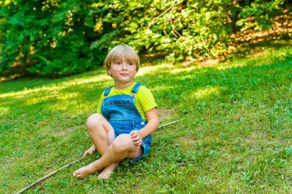 Mały chłopiec gra na zewnątrz na ładny słoneczny letni dzień noszenia ubrania robocze drelich — Zdjęcie stockowe