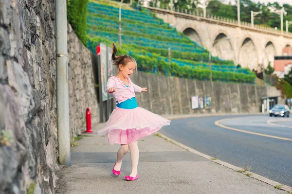 Retrato al aire libre de una linda niña de 7 años, caminando a la escuela de baile y bailando en la calle, vistiendo vestido de ballet púrpura — Foto de Stock