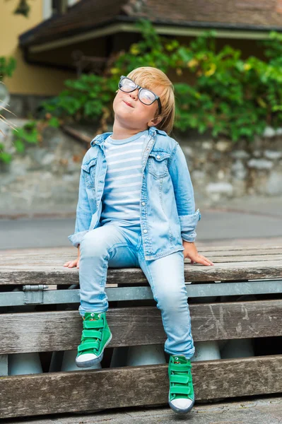 Portrait extérieur d'un mignon petit garçon en lunettes, portant des vêtements en denim et des chaussures vertes — Photo