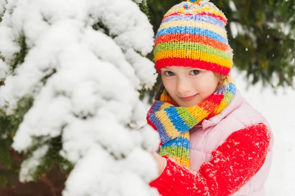 冬天的可爱的小姑娘在降雪下, 穿红毛衣、 色彩鲜艳的帽子和围巾的肖像 — 图库照片
