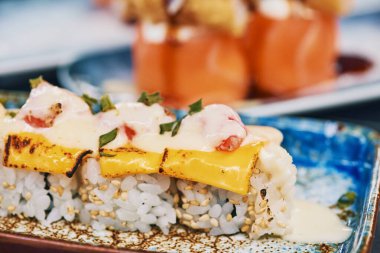 Erimiş peynir ve somonla suşi görüntüsünü kapat.