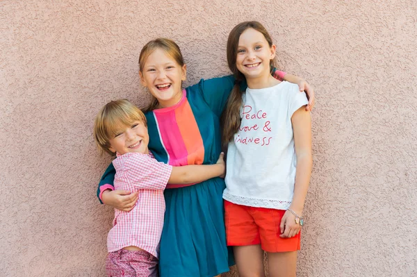 Venkovní 3 roztomilých dětí, nosí barevné oblečení, stojící proti růžové zdi portrét — Stock fotografie