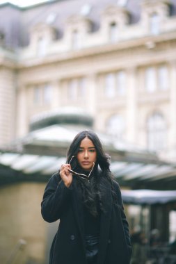 Avrupa 'nın caddesinde elinde güneş gözlüğü olan şık bir genç kadın. Siyah ceketli kendine güvenen bir kadın. Şehir seyahati alanında tarihi bir geçmişi var.