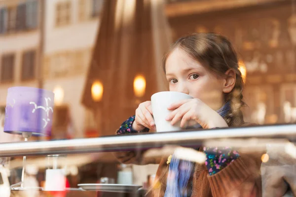 Niña bebiendo chocolate caliente en un café —  Fotos de Stock