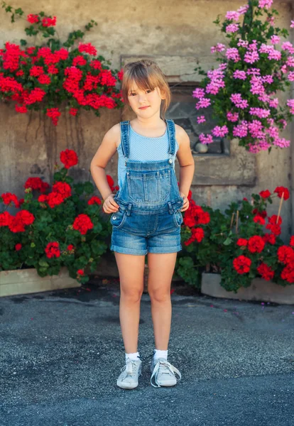 Retrato de verão de uma menina de 6 anos de idade, vestindo macacão jeans e sapatos cinza — Fotografia de Stock