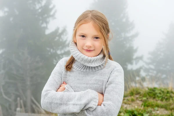 Cute little girl of 8 years old playing outdoors on a very foggy day, wearing grey warm pullover — Stock Photo, Image