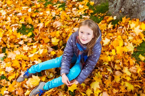 Herfst portret van een schattig klein meisje van 8 jaar oud, spelen met gele bladeren in het park — Stockfoto