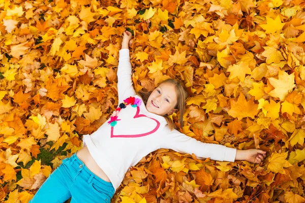 Herfst portret van een schattig klein meisje van 8 jaar oud, spelen met gele bladeren in het park — Stockfoto