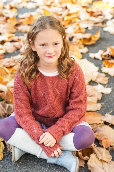 Podzimní portrét roztomilá holčička s kudrnatými vlasy, nosí svetr terakotové, nohu ohřívačů a modré boty — Stock fotografie